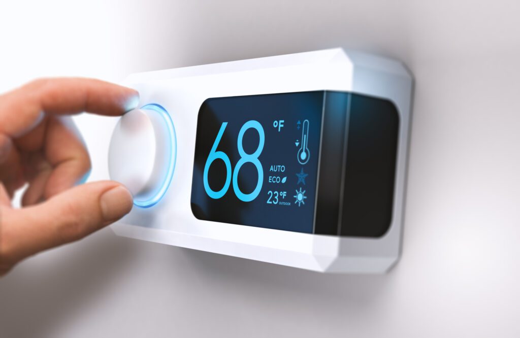 close-up of hand adjusting temperature setting on a smart thermostat
