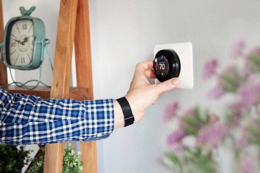 Man turning down thermostat to improve heat pump efficiency 